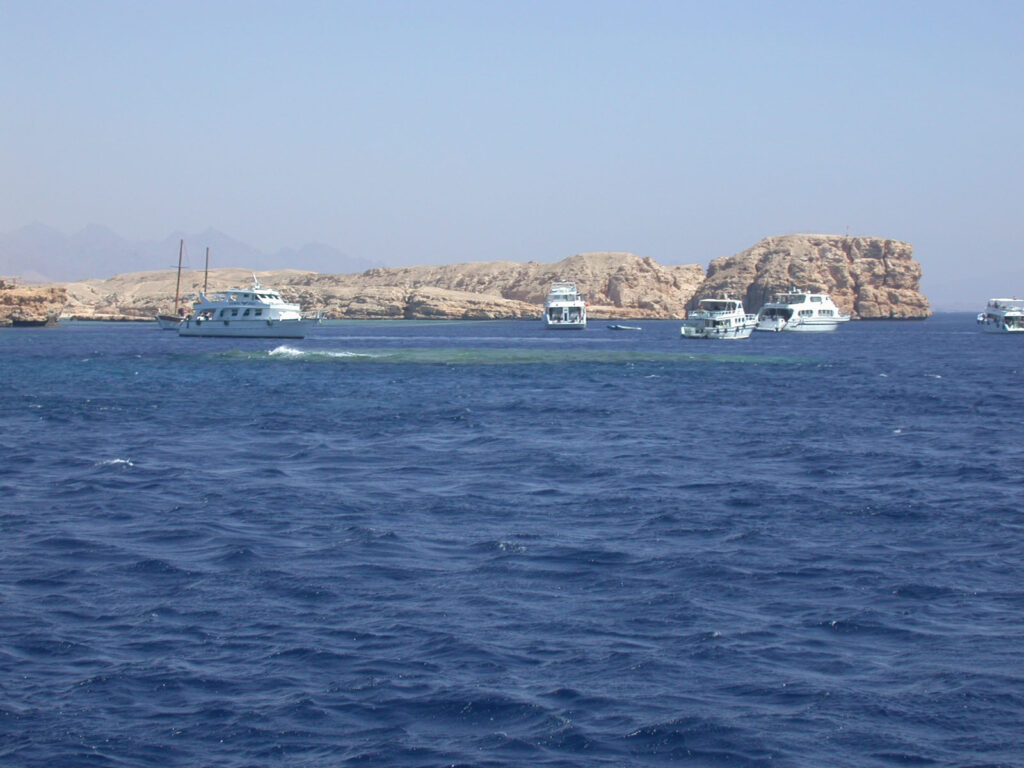 Barcos de buceo fondeados frente a los acantilados claros de Ras Mohammed, sobre Shark y Yolanda Reef