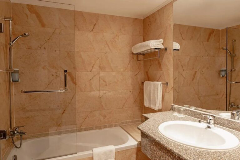 Un baño de mármol con bañera, ducha y lavabo