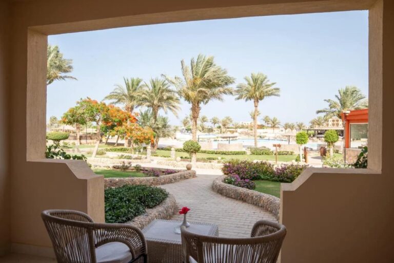 Una terraza con dos sillones trenzados, frente a los jardines en flor y las palmeras del Blend Elphistone Resort