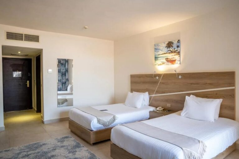 Una habitación con dos camas, cabecera de madera clara y un cuadro de playa
