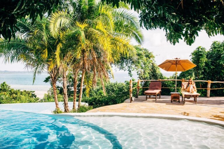 La piscina infinita, sus tumbonas y su sombrilla naranja, frente al mar