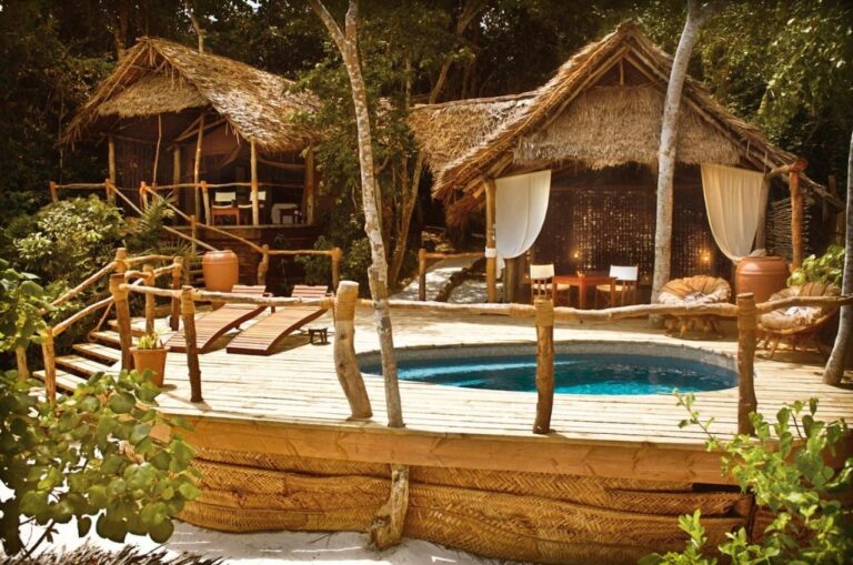 Dos bungalows con techo de paja y una terraza de madera con piscina pequeña y dos tumbonas