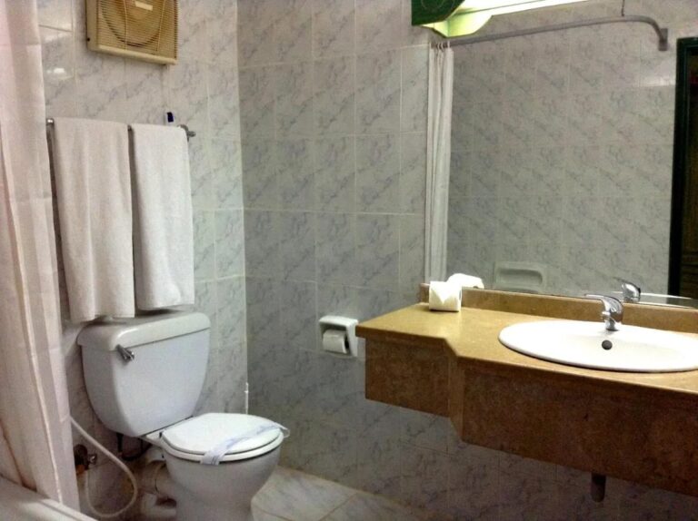 Un baño con azulejos grises, un lavabo sobre encimera y una cortina de ducha