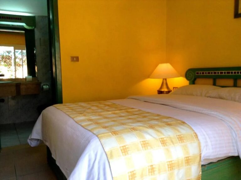 Una habitación de paredes amarillas con cama grande y la puerta del baño abierta