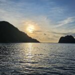 La isla del Coco a contraluz al atardecer, con un barco de crucero fondeado a la derecha y el mar en calma