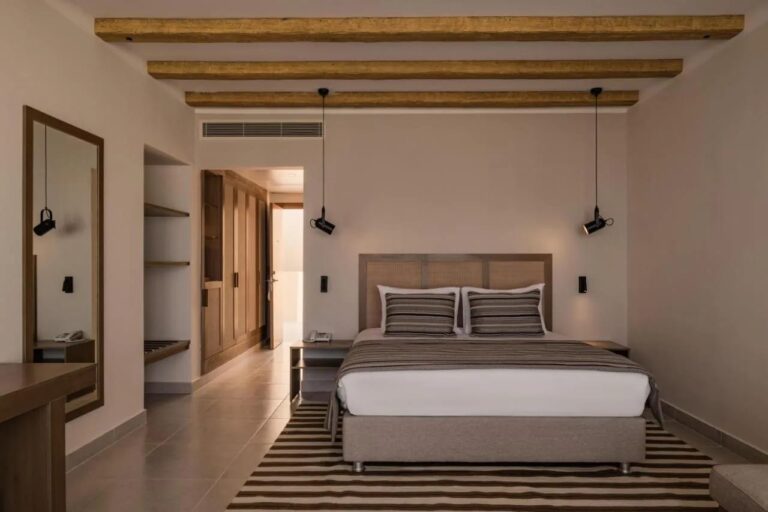 Una habitación con cama grande bajo un techo de vigas vistas