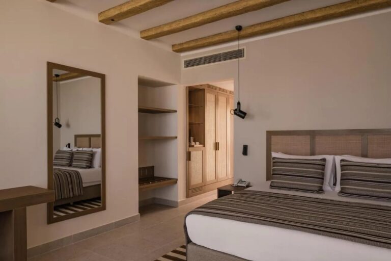 Una habitación con cama grande, un espejo grande y un vestidor abierto