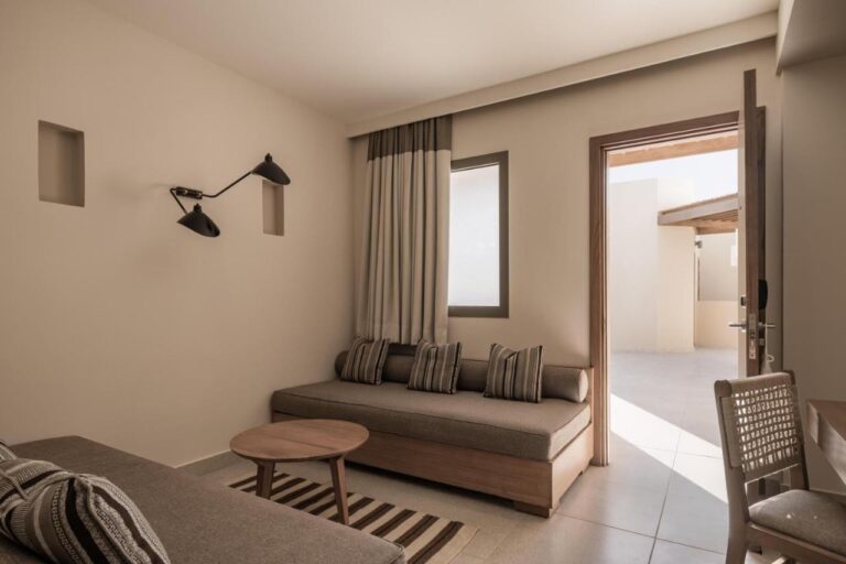 La zona de estar de una habitación, con un banco acolchado y una puerta abierta al exterior