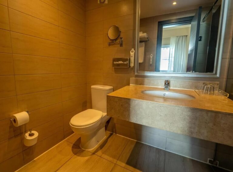 Un baño con azulejos, inodoro, lavabo y espejo grande