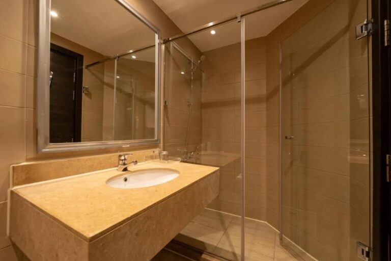 Un baño con lavabo, espejo grande y ducha con mampara de vidrio