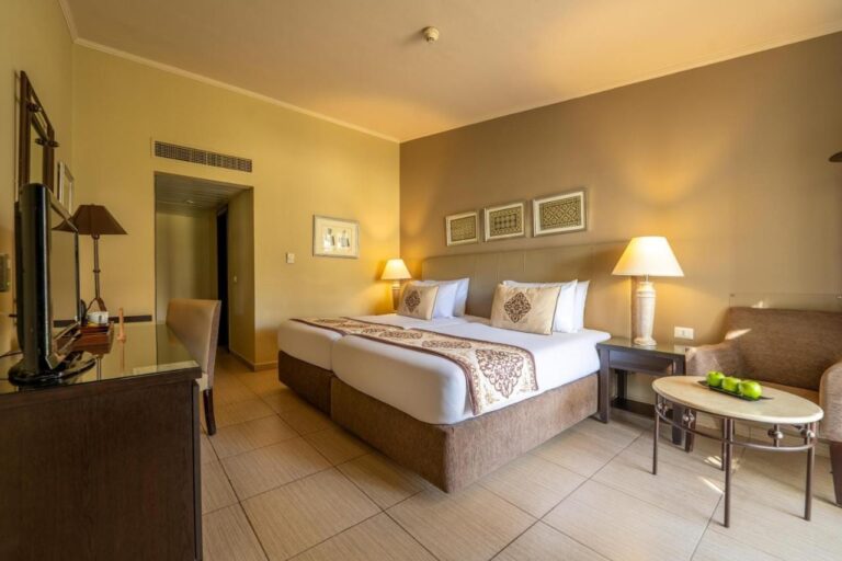 Una habitación con dos camas, un sillón y una mesa baja con manzanas verdes