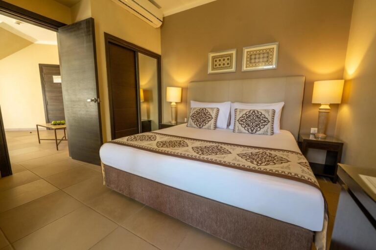 Una habitación con cama grande, un armario con espejo y una puerta abierta a otra estancia
