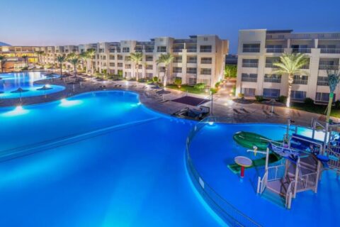 Las piscinas iluminadas del JAZ Soma Beach al anochecer, entre los edificios y las palmeras