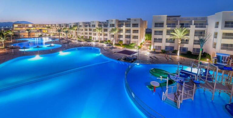 Las piscinas iluminadas del JAZ Soma Beach al anochecer, entre los edificios y las palmeras