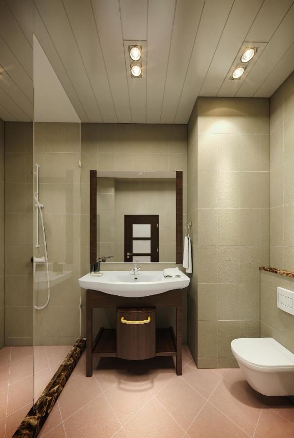 Un baño con ducha de vidrio, lavabo sobre mueble de madera e inodoro