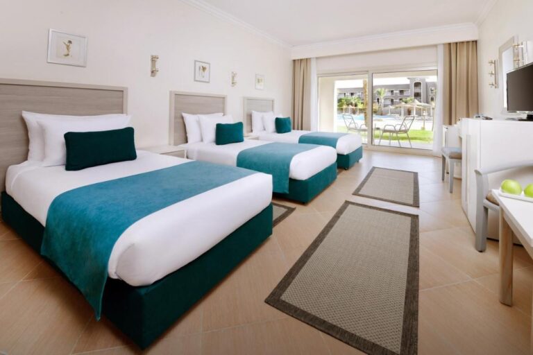 Una habitación con tres camas y muebles claros, abierta a una terraza frente a la piscina
