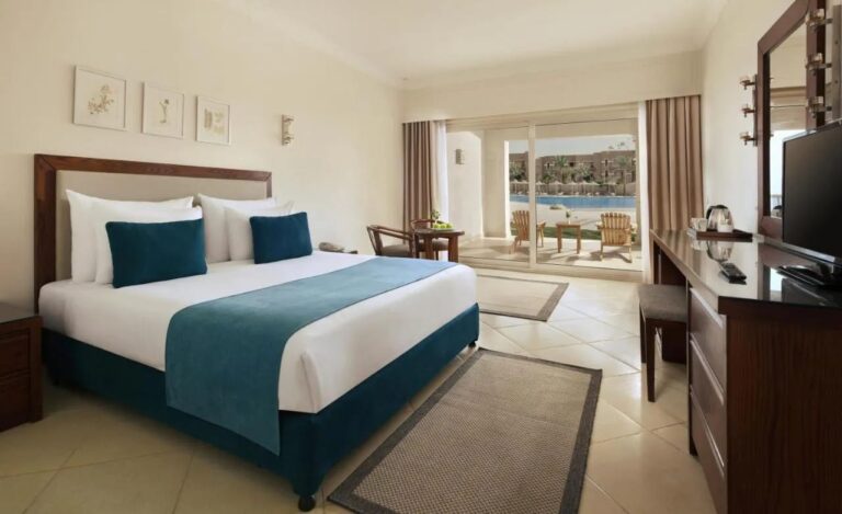 Una habitación con cama grande y muebles de madera oscura, con una terraza frente a la piscina