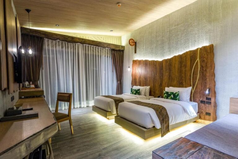 Una habitación con dos camas iluminadas desde abajo, un escritorio y cortinas translúcidas