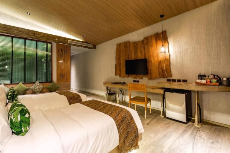 Una habitación con dos camas, un banco bajo la ventana, un escritorio y una bandeja de té