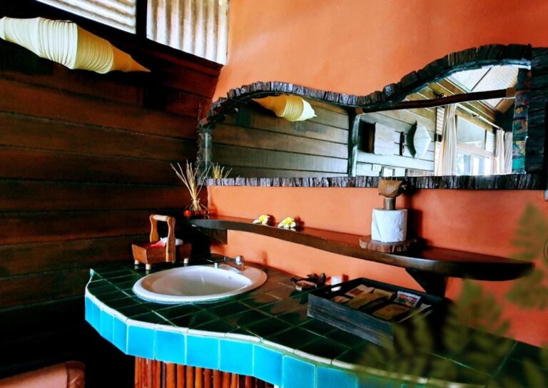 Un lavabo sobre una encimera de mosaico turquesa, bajo un espejo con marco de madera