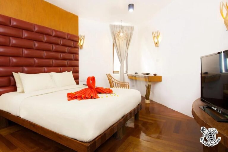 Una habitación blanca del Koh Tao Cabana, con cama grande, cabecera roja acolchada y televisor