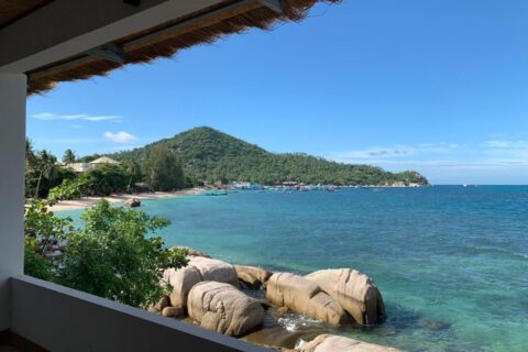 La bahía y sus rocas vistas desde una terraza cubierta del Koh Tao Heritage, con barcos fondeados