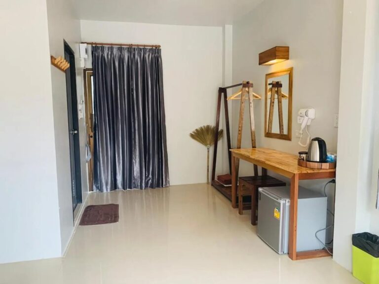 La entrada de una habitación, con una cortina gris, un perchero y un escritorio de madera