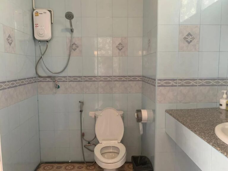 Un baño con azulejos, ducha con calentador, inodoro y lavabo