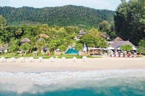 El Layana Resort visto desde el mar, con su playa, sus sombrillas blancas, su piscina y sus techos bajo las palmeras