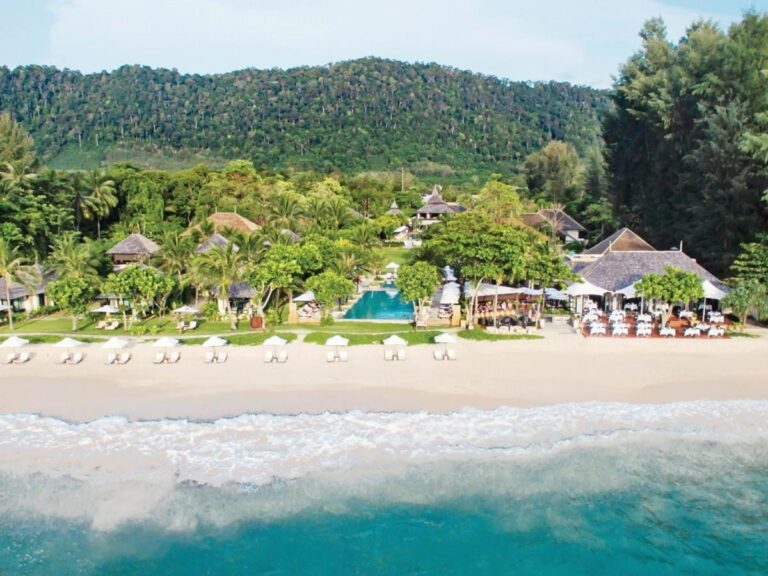El Layana Resort visto desde el mar, con su playa, sus sombrillas blancas, su piscina y sus techos bajo las palmeras