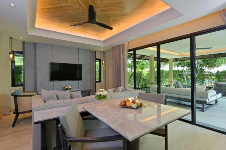 Un salón con mesa de mármol y sofá, abierto a una terraza cubierta