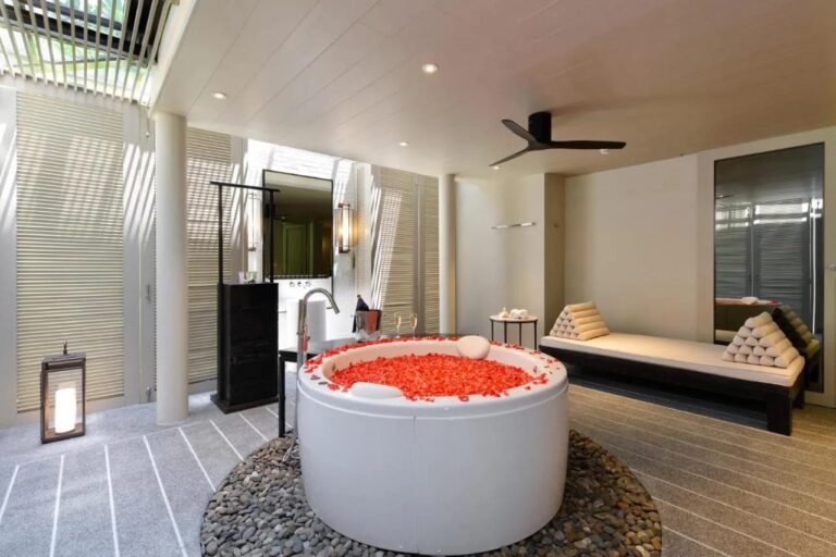 Una bañera redonda llena de pétalos rojos, sobre un lecho de guijarros