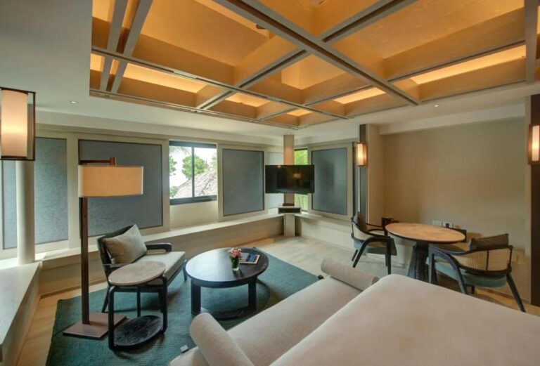 La zona de estar de una habitación, con un sillón, una mesa baja redonda y una mesa para dos