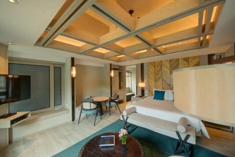 Una habitación con cama grande, una mesa para dos junto a la ventana y un televisor