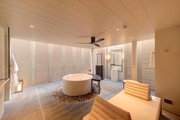 Un baño del Layana Resort con una bañera redonda sobre guijarros y una bata colgada