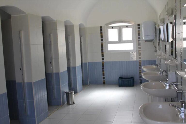 Un bloque de baños con cabinas en fila y una hilera de lavabos