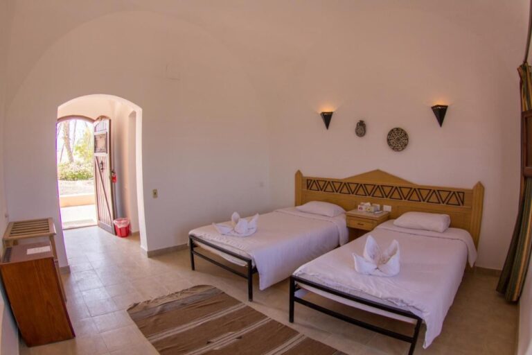 Una habitación con dos camas y una entrada abovedada abierta al jardín