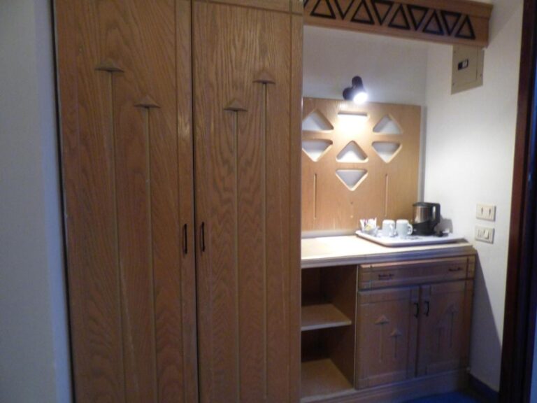 Un gran armario de madera y un mueble con un hervidor y tazas