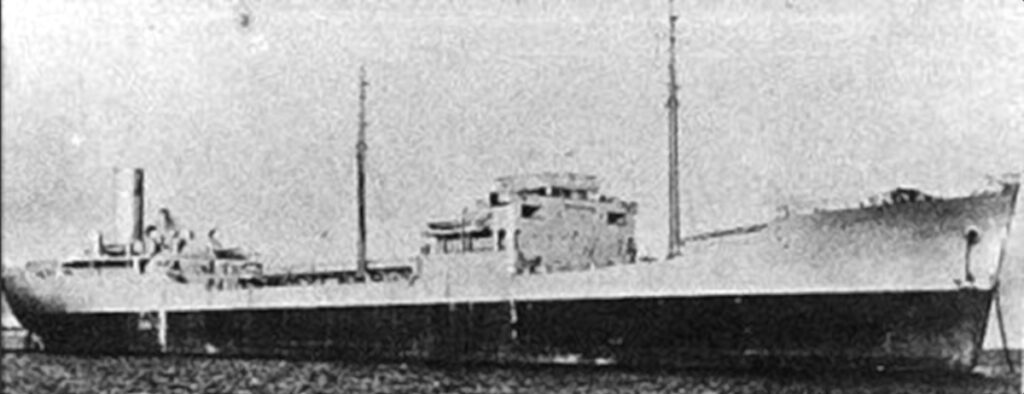 Foto de archivo en blanco y negro, granulosa, de un petrolero de perfil, con el puente en el centro, dos mástiles y la chimenea en la popa.