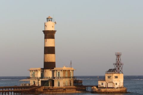 El faro de Daedalus, una torre de franjas blancas y negras sobre el arrecife, con sus edificios y su muelle metálico, al atardecer