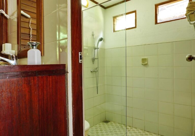 Un baño con un mueble de madera y una ducha tras una mampara de vidrio
