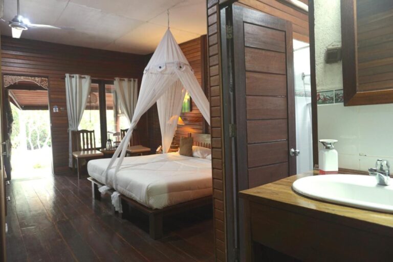 Una habitación con cama grande con mosquitero y un lavabo en primer plano