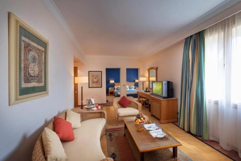 Un salón con muebles de ratán y, al fondo, una habitación de pared azul