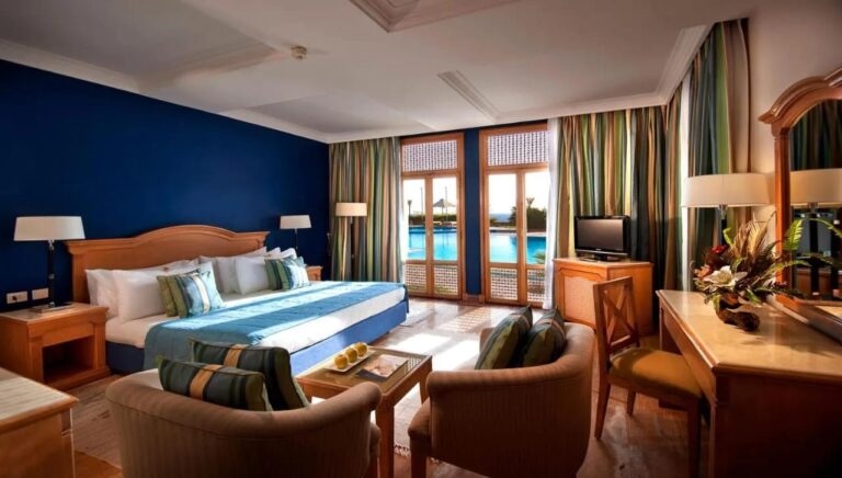 Una habitación con cama grande, una pared azul y puertas acristaladas que dan a la piscina