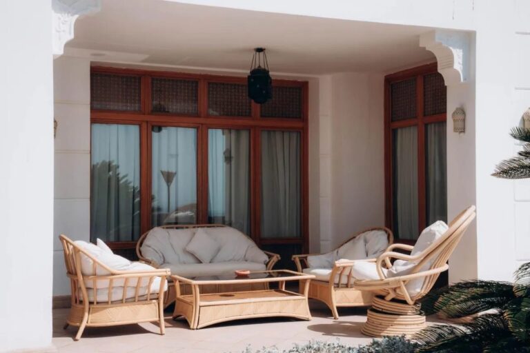 Una terraza cubierta con un sofá y sillones de ratán
