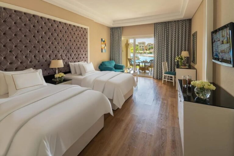 Una habitación con dos camas grandes y suelo de parqué, abierta a la piscina