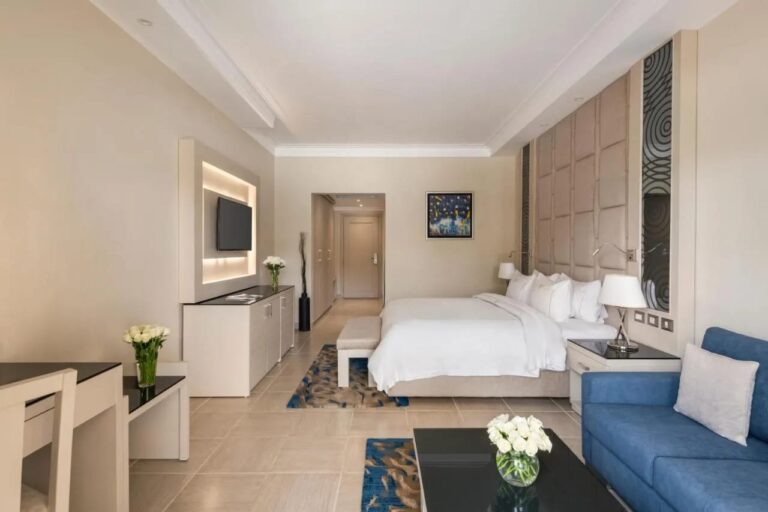 Una habitación con cama grande, un sofá azul y una televisión en la pared