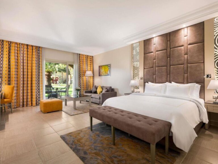 Una habitación con cama grande, una zona de estar y una puerta acristalada que da al jardín