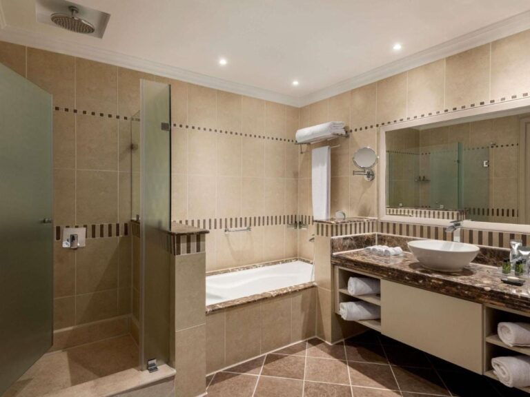 Un baño con ducha de cristal, bañera y lavabo sobre encimera