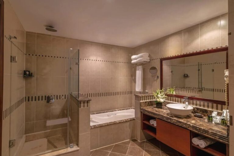 Un baño con ducha de cristal, bañera y espejo grande